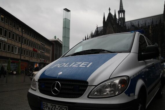 Polizeiauto vor Kölner Dom; zwei Männer mit Schusswaffen bei Kontrolle festgenommen.