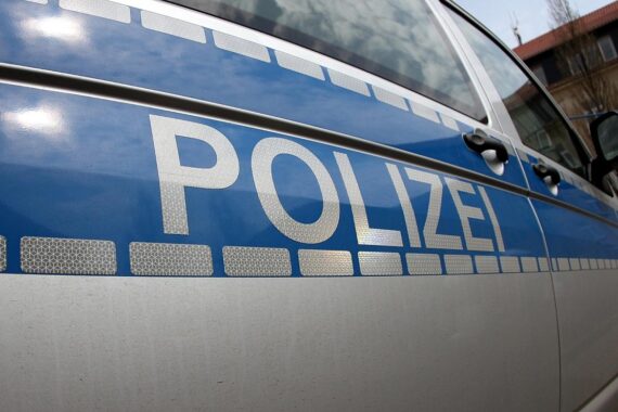 Eine verletzte Radfahrerin nach Pedelec-Unfall, Polizeiauto und Rettungswagen im Hintergrund.