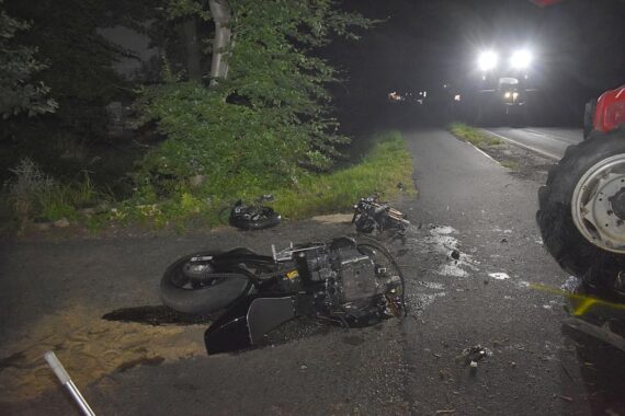 Zerstörtes Motorrad nach Unfall mit Traktor, Polizei und Feuerwehr sichern den Unfallort.