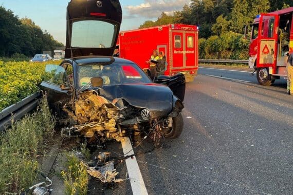 Schwerer Verkehrsunfall: VW Beetle kollidiert, Motorblock brennt, Fahrer schwer verletzt. Feuerwehr im Einsatz.