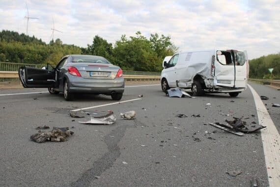 Verkehrsunfall: schwer beschädigte Autos, Rettungskräfte, Unfallstelle auf Landstraße, gesperrte Fahrbahn.