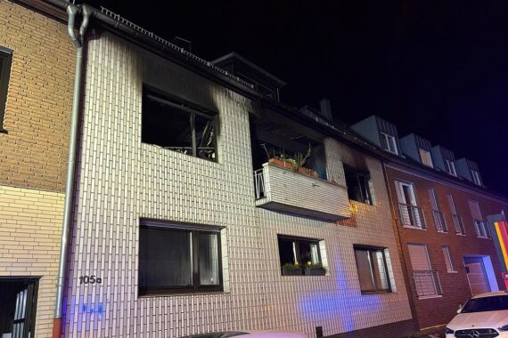 Feuerwehr beim Löschen eines Gebäudebrands, zerstörtes Haus, Verletzter, Einsatzkräfte vor Ort.