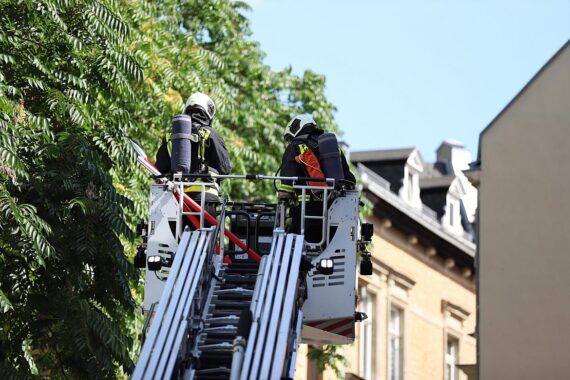 Brandlöschaktion der Feuerwehr in einem Mehrfamilienhaus, verletzter Bewohner wird gerettet.