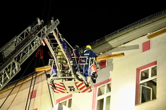Ehrenamtliche THW-Kräfte sichern einsturzgefährdeten Dachstuhl in Berlin mit Greifzügen und Stahlseilen.