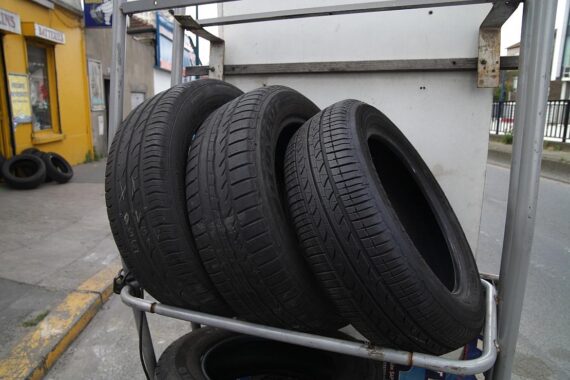 Beschädigte Autoreifen auf einem Parkplatz, umgeben von umweltpolitischen Schreiben und Polizeiabsperrungen.