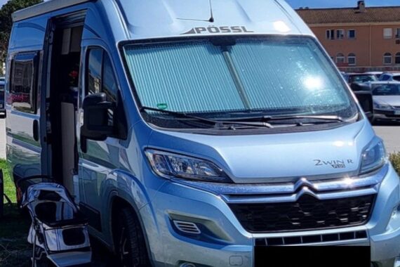 Ein gestohlenes Wohnmobil vor einer Stadtlandschaft, mit einer polizeilichen Präsenz zur Aufklärung.