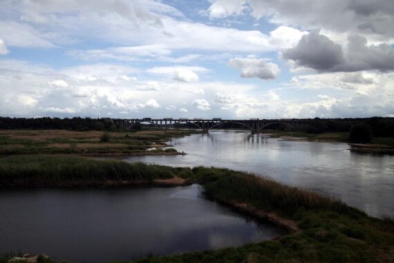 Flusslandschaft mit Wolken und Sonnenschein, symbolisiert wechselhaftes Wetter in Berlin-Brandenburg.