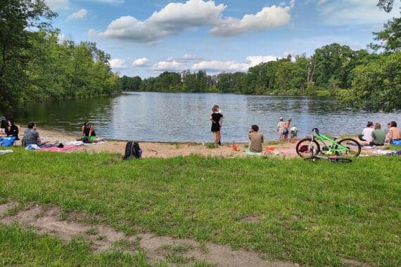 Ein sonniger Badestrand mit Menschen, die sich am Wasser und Sand entspannen.