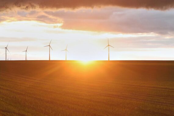 Windräder vor einem klaren Himmel, symbolisieren freundliches und warmes Wetter in Niedersachsen.