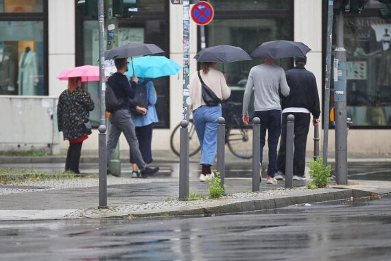 Personen mit Regenschirmen in regnerischer, bewölkter Atmosphäre, typisches Wetter für Niedersachsen.