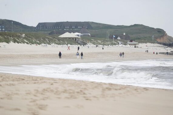 Strand mit Sonne und Wolken, Nordsee, frischer Wind, Menschen genießen das Wetter.