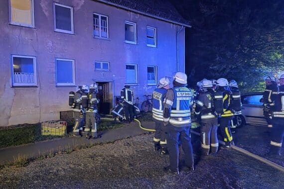Feuerwehr im Einsatz bei nächtlichem Zimmerbrand, Rettung von Verletzten und Löscharbeiten.