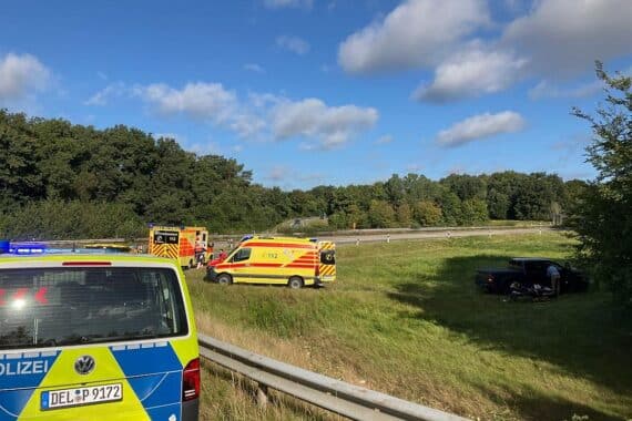 Eine Autobahneinfahrt mit einer Familie, Rettungswagen und Verkehrssicherheitsmaßnahmen.