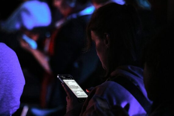 Junge Frau nutzt Smartphone in einem schulischen Umfeld, umgeben von Bildungssymbolik und Technologie.