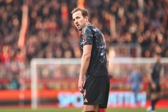 Harry Kane jubelt nach Tor, umgeben von jubelnden Bayern-Spielern im Stadion.