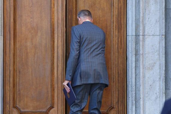 Friedrich Merz steht besorgt vor einer politischen Grafik, die Wahlumfragen zeigt.