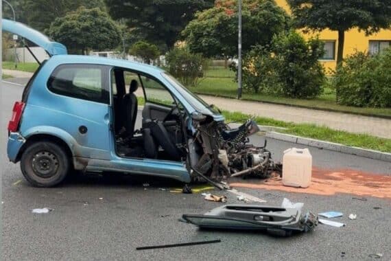 Schwerer Verkehrsunfall: beschädigtes Fahrzeug, Einsatzkräfte, Straßenabsperrung, verletzte Beifahrerin in Klinik.