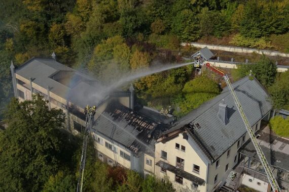 Feuerwehr im Einsatz: Löscharbeiten an brennendem Gebäude, starke Rauchentwicklung, Einsatzkräfte aktiv.