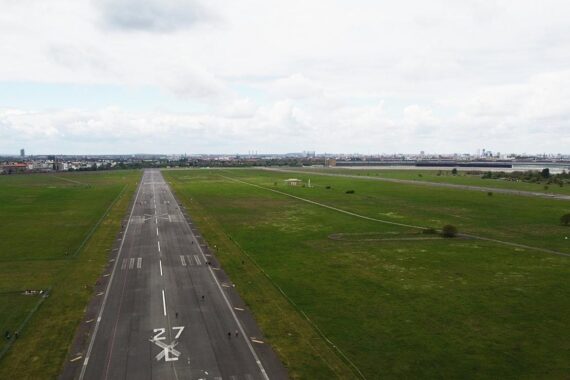Tempelhofer Feld mit viel Grün, Sportflächen, Bänken und Menschen in Freizeitaktivitäten.