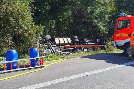 Zwei Lastwagen kollidieren auf Autobahn, Sattelzug kippt in Böschung, Fahrer leicht verletzt.