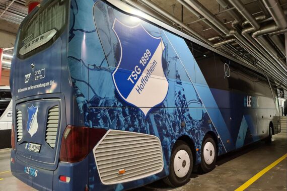 Mannschaftsbus der TSG Hoffenheim vor Gerichtsgebäude, symbolisiert aufhobene Stadionverbote für Spielerberater.
