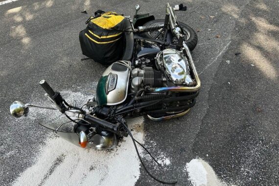 Motorradunfall: beschädigtes Motorrad, Rettungskräfte vor Ort, Polizei sperrt Straße nach Frontalzusammenstoß.