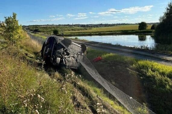 Schwerer Unfall auf Autobahn mit umgekertem Auto, Verletzten und aufgerissener Leitplanke.