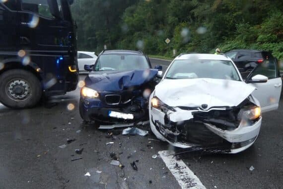 Zwei beschädigte Autos nach Unfall, Polizei und Rettungswagen vor Ort, Verletzter abtransportiert.