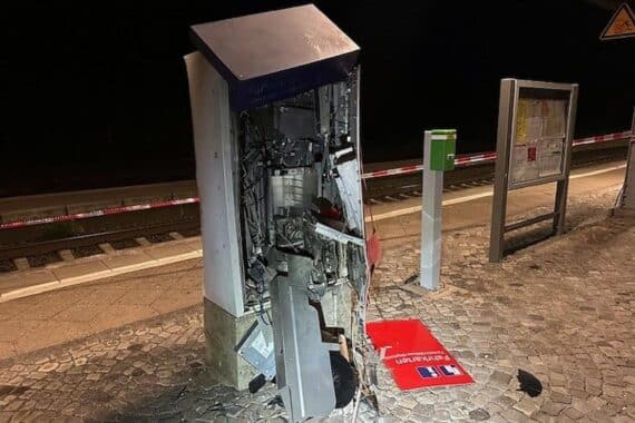 Zerstörter Fahrkartenautomat, Polizei vor Ort, verstreute Geldscheine und Geldkassetten.