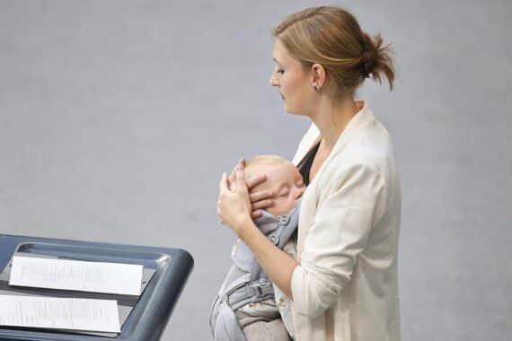 Hanna Steinmüller hält ein Baby in einer Trage während ihrer Bundestagsrede.