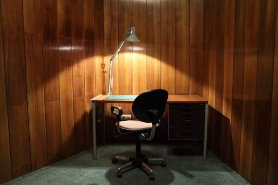 Leerer Schreibtisch mit Laptop und Notizen, symbolisiert Personalabbau und verhaltene Arbeitsmarktlage.