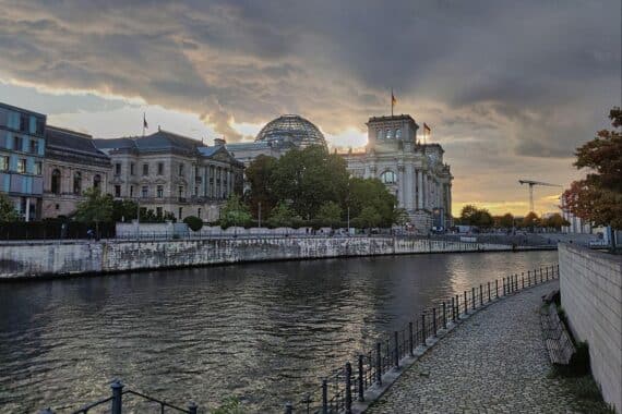 Sonnenuntergang über dem Reichstagsgebäude, herbstliche Farben und ruhige Atmosphäre in Berlin.