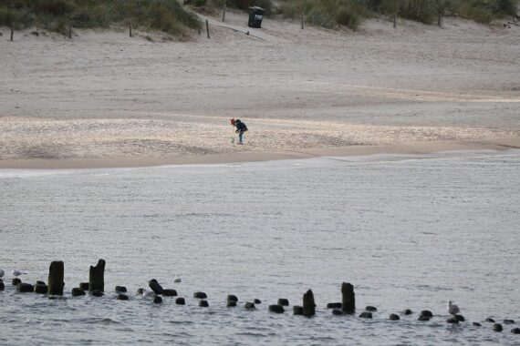 Kind am Strand, Sonne und Wolken, symbolisiert das wechselhafte Wetter in Niedersachsen.