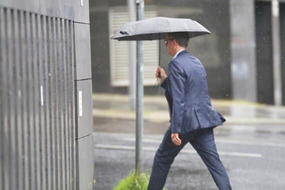 Mann mit Regenschirm im Regen, symbolisiert wechselhaftes Wetter mit Gewittern in Sachsen-Anhalt.