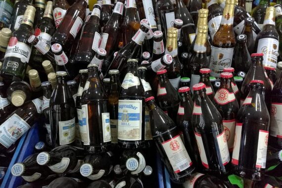 Zwei Männer im Supermarkt trinken Bier, nachdem sie ins Getränkelager eingebrochen sind.
