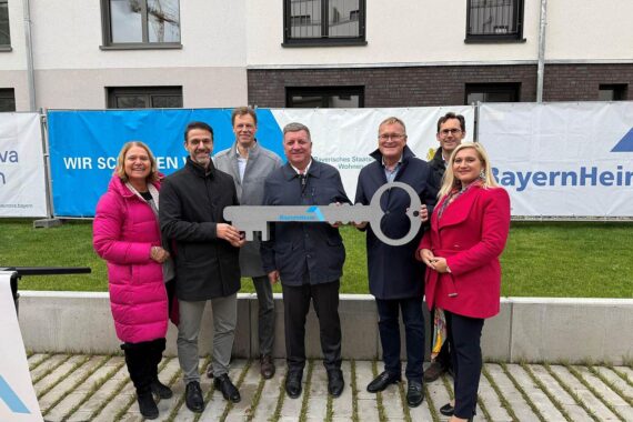 Zwei fünfgeschossige Wohngebäude mit Balkonen auf gelbem Hintergrund, symbolisieren neue, bezahlbare Wohnungen in Bamberg.
