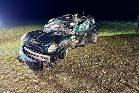 Völlig zerstörter Mini nach Unfall, Feuerwehr befreit Fahrer, Polizei sichert Unfallstelle.