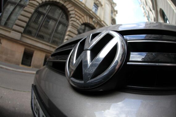 VW-Logo vor der Gläsernen Manufaktur mit Hinweis auf Entlassungen und Standortproblematik.