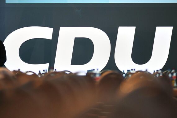 CDU-Logo vor einem Hintergrund von Hamburg-Altona, symbolisiert Verzögerung beim Bahnhofsbau.