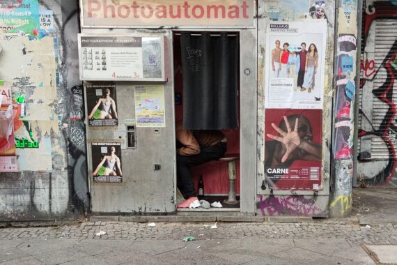 Obdachloser im Photoautomaten, symbolisiert Einsamkeit und Verelendung in urbanen Räumen.