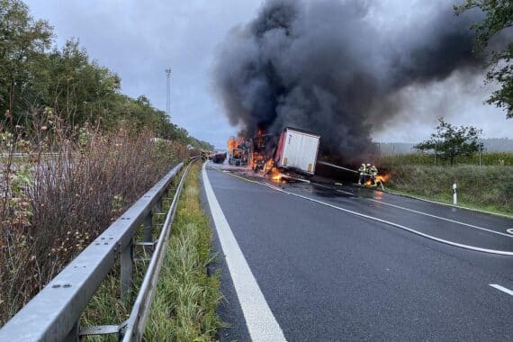Einsatzkräfte der Feuerwehr löschen brennende Lkw nach schwerem Unfall auf Autobahn.