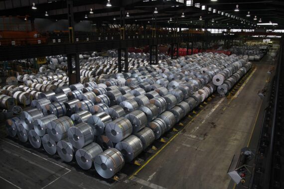 Industrieanlage mit Stahlproduktion, Maschinen und Arbeitern; symbolisiert Export von Eisen und Stahl.