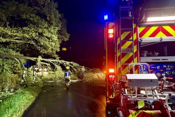 Umgestürzter Baum blockiert Straße, Feuerwehr Hünxe beseitigt Sturmschaden mit Motorsägen.