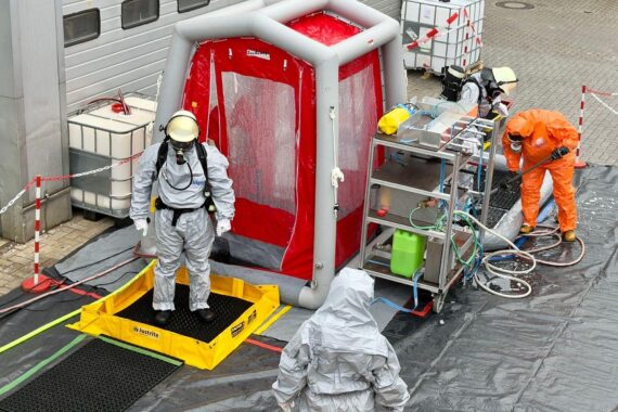 Einsatzkräfte in Chemikalienschutzanzügen sichern Austritt von Salzsäure bei Industriebetrieb in Ganderkesee.