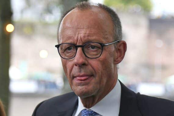 Friedrich Merz steht in einer Menschenmenge, diskutiert aktuelle Gehaltserhöhungen für politische Ämter.