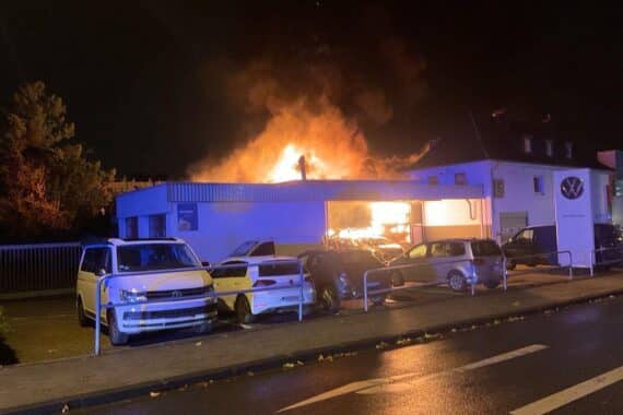 Großbrand in Mülheimer Autowerkstatt, Feuerwehr kämpft mit Löschfahrzeugen gegen Flammen.