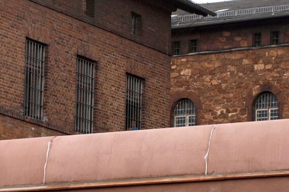 Ein Gefängnis mit Sicherheitszäunen und tristen Bedingungen, symbolisiert Trauer und Isolation.