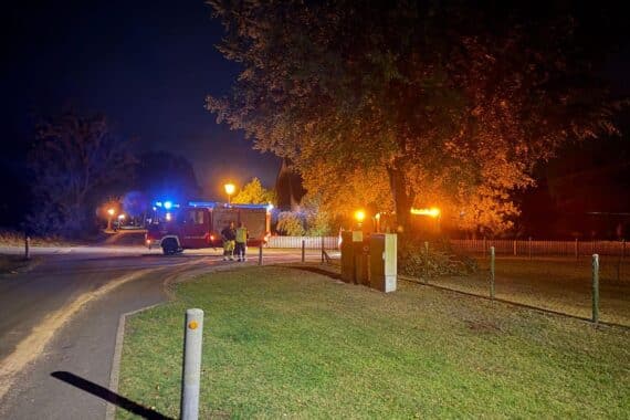 Feuerwehr reinigt Ölspur auf Straße, Einsatzkräfte streuen Bindemittel zum Schutz des Verkehrs.