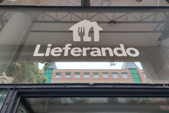 Lieferando-Fahrer bei der Arbeit, symbolisieren prekäre Arbeitsbedingungen und drohende Stellenstreichungen.