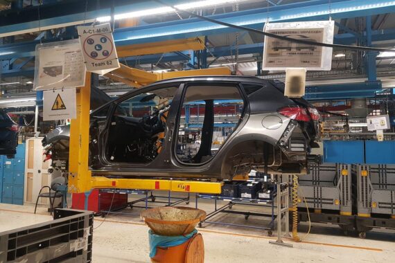 Rückgang der Autoproduktion in Deutschland; fabrikähnliche Szenerie mit Maschinen und Autos im Hintergrund.